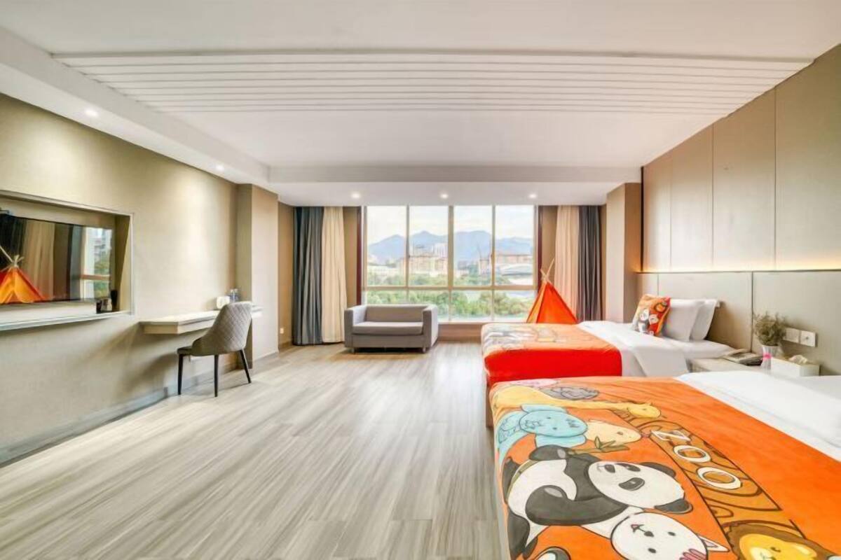 Een hotelkamer met een bed, bureau, stoel en uitzicht op de stad.