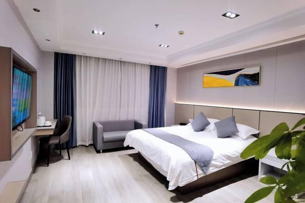 Een moderne hotelkamer met een bed, bureau, stoel en televisie.