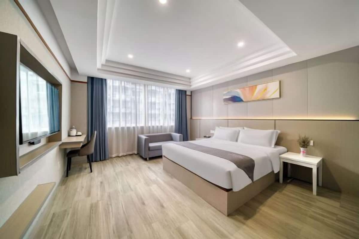 Een moderne hotelkamer met een groot bed, een bureau, een stoel en een televisie.