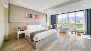 Een moderne hotelkamer met een groot bed, een badkuip en uitzicht over de stad.
