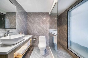 Uma casa de banho moderna com uma grande lavatório branco, uma sanita e um compartimento de duche com cabine de vidro.