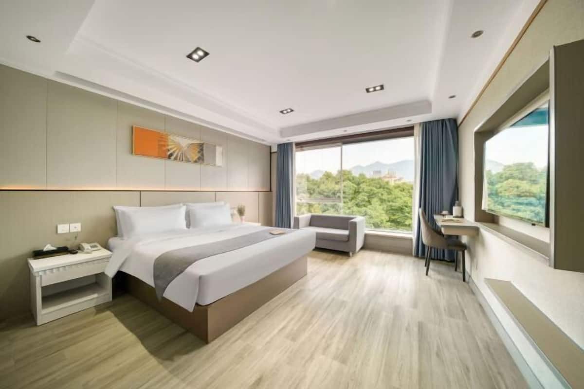 Een moderne hotelkamer met een groot bed, een bureau en uitzicht op groen.
