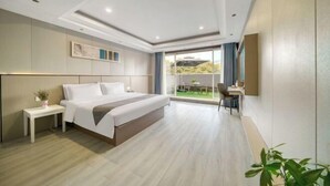 Een moderne hotelkamer met een groot bed, een bureau en uitzicht op de omgeving.