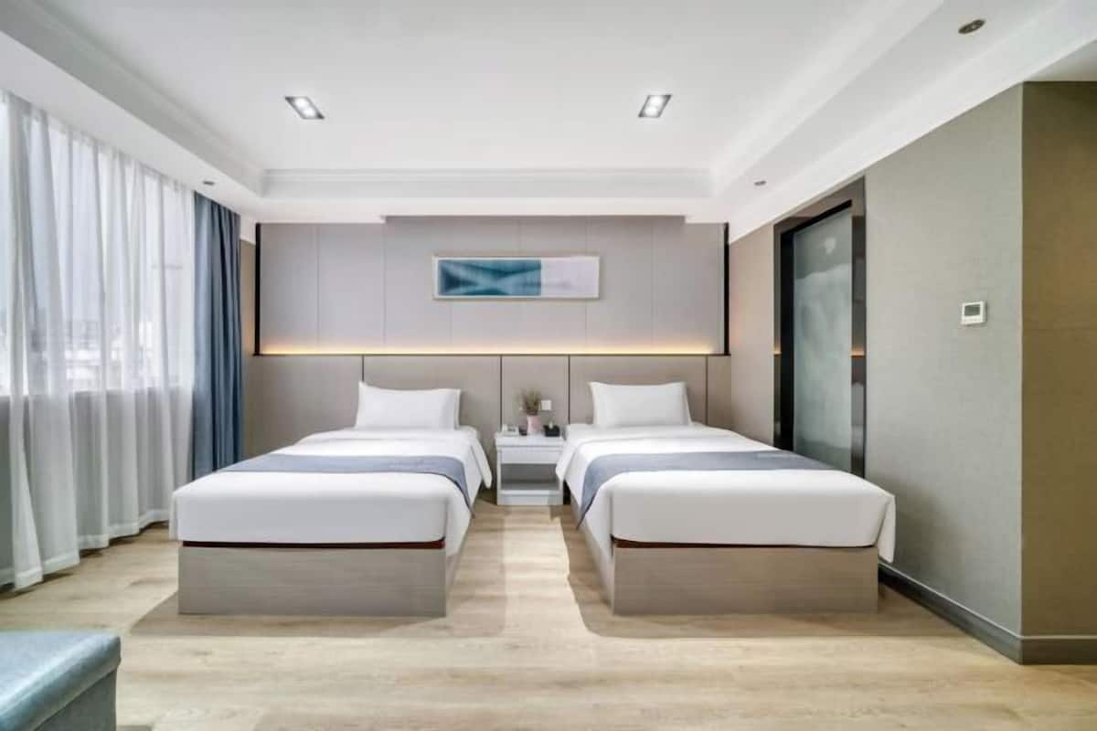 Een moderne hotelkamer met twee bedden, een nachtkastje, een kunstwerk aan de muur en een schuifdeur.