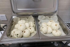 Una vaporera con dos canastas de panecillos blancos.