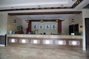 A reception area with a reception desk, decorative wall panels, and a patterned floor. - Chamagudao Hotel (Ningbo)