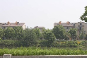 A residential area with buildings, trees, and a body of water. - Chamagudao Hotel (Ningbo)
