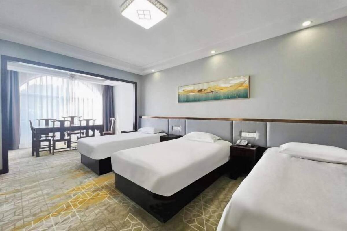 A hotel room with two beds, a desk, and a chair.