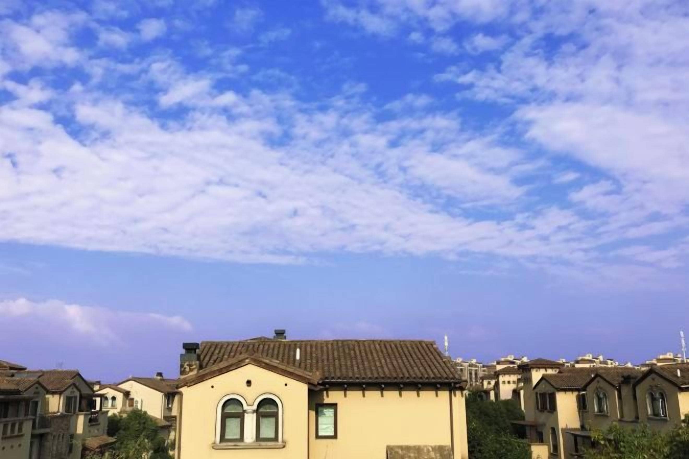 A residential area with multiple houses, each with a distinct architectural style, under a partly cloudy sky.