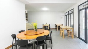 A conference room with a round wooden table, black chairs, and a small plant. - Hongfu Inn (Zhoushan)