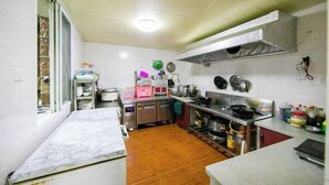 A compact kitchen with a wooden floor, stainless steel appliances, and a window with a view. - Hongfu Inn (Zhoushan)