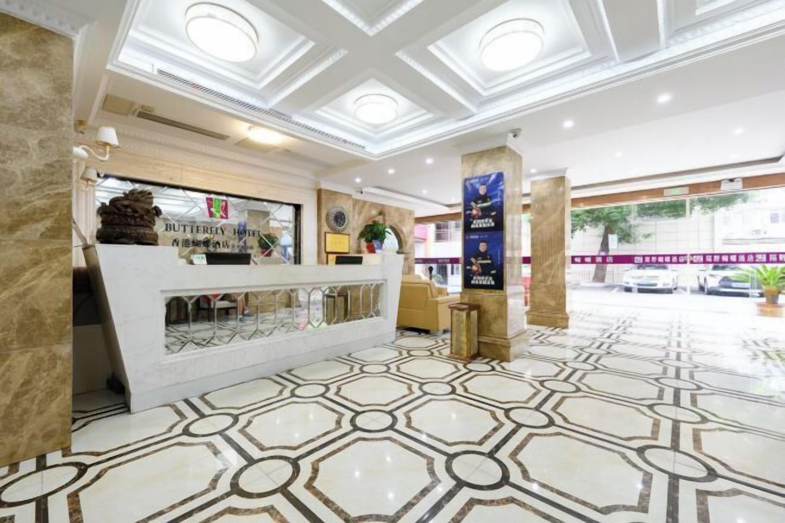 A hotel reception area with a marble floor, a reception desk, and a sign for the Butterfly Hotel.