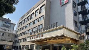 A hotel with a modern facade, multiple floors, and a prominent entrance with a covered area. - Xianggang Hudie Hotel (Anqing)