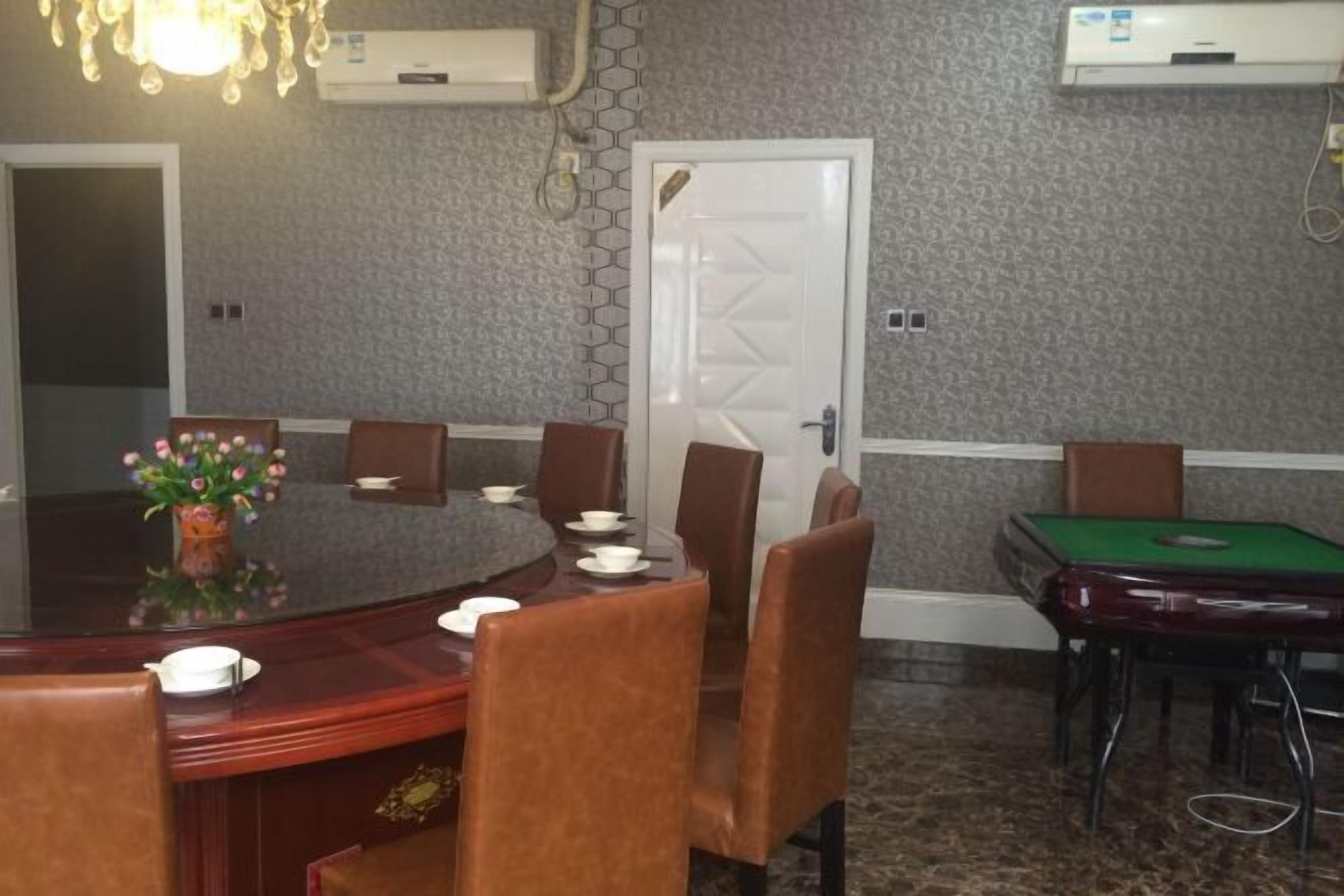 A conference room with a round table, brown leather chairs, a vase of flowers, and a pool table.