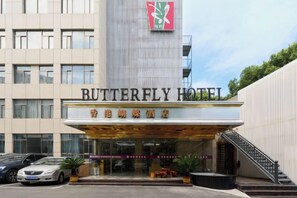 A hotel entrance with a modern facade, a staircase, and a parking area.