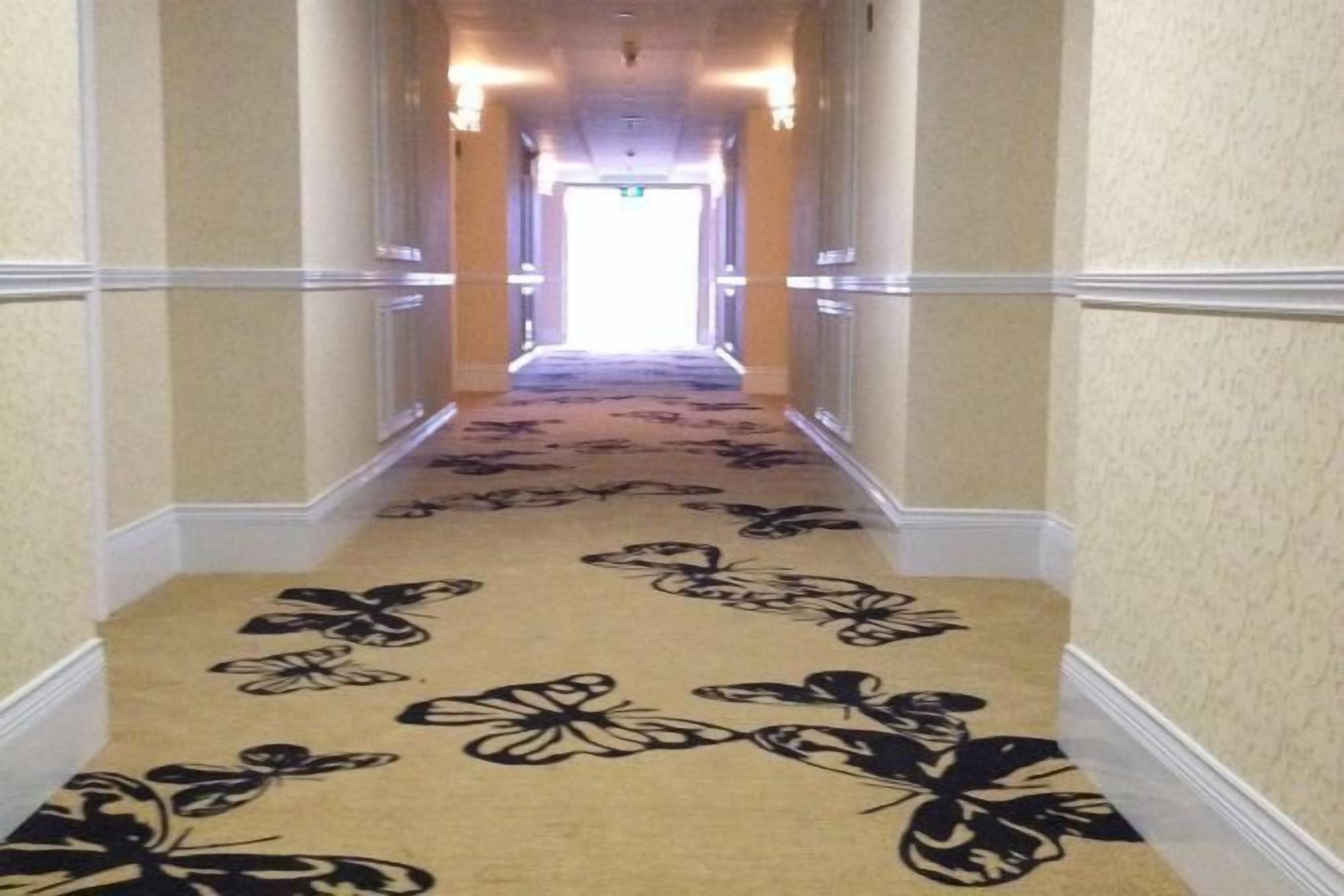 A hotel hallway with a carpet featuring a floral pattern.