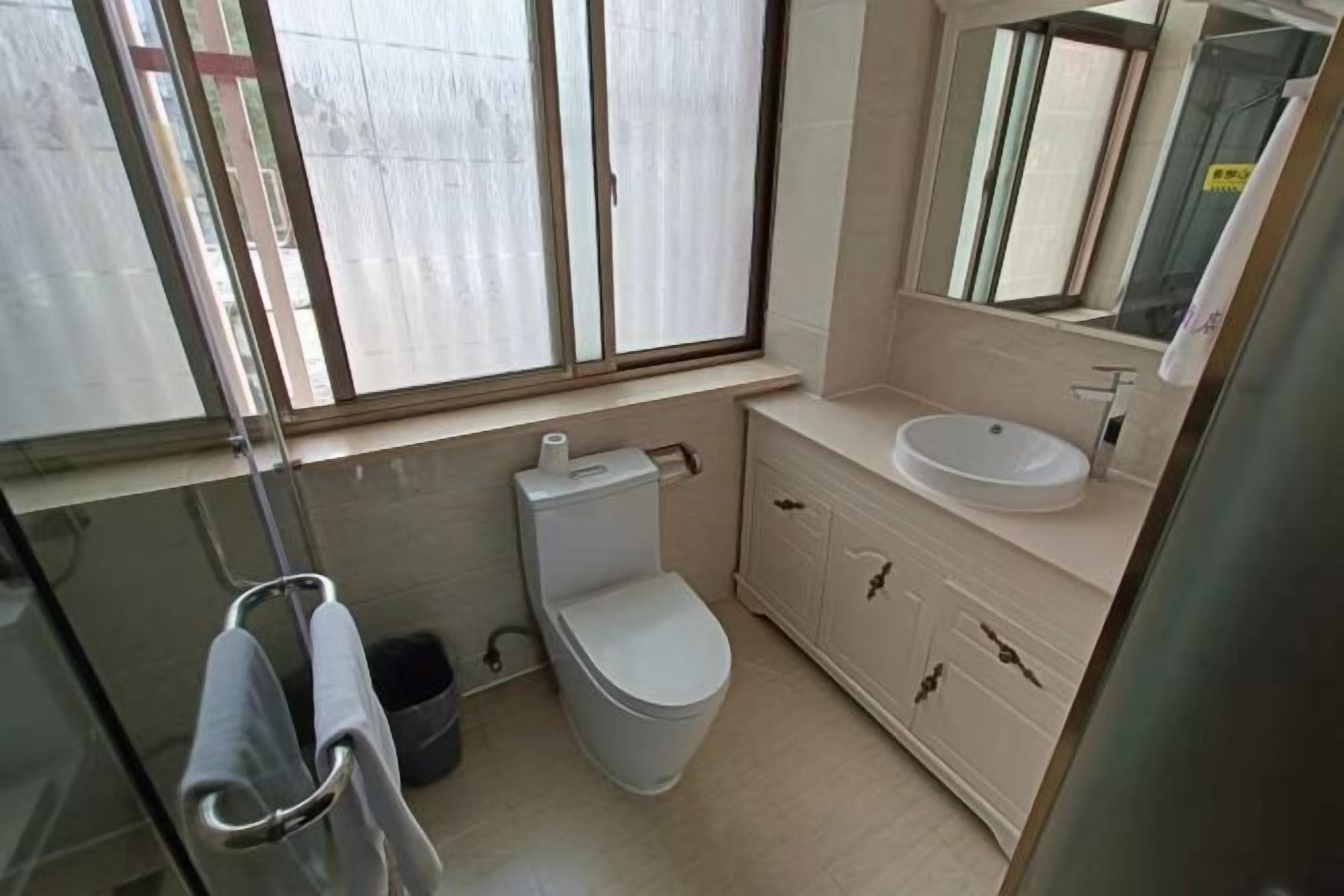 A bathroom with a toilet, sink, and mirror.