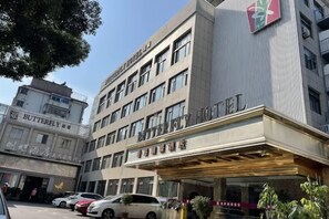 A hotel with a prominent sign, multiple floors, and a parking area with cars.