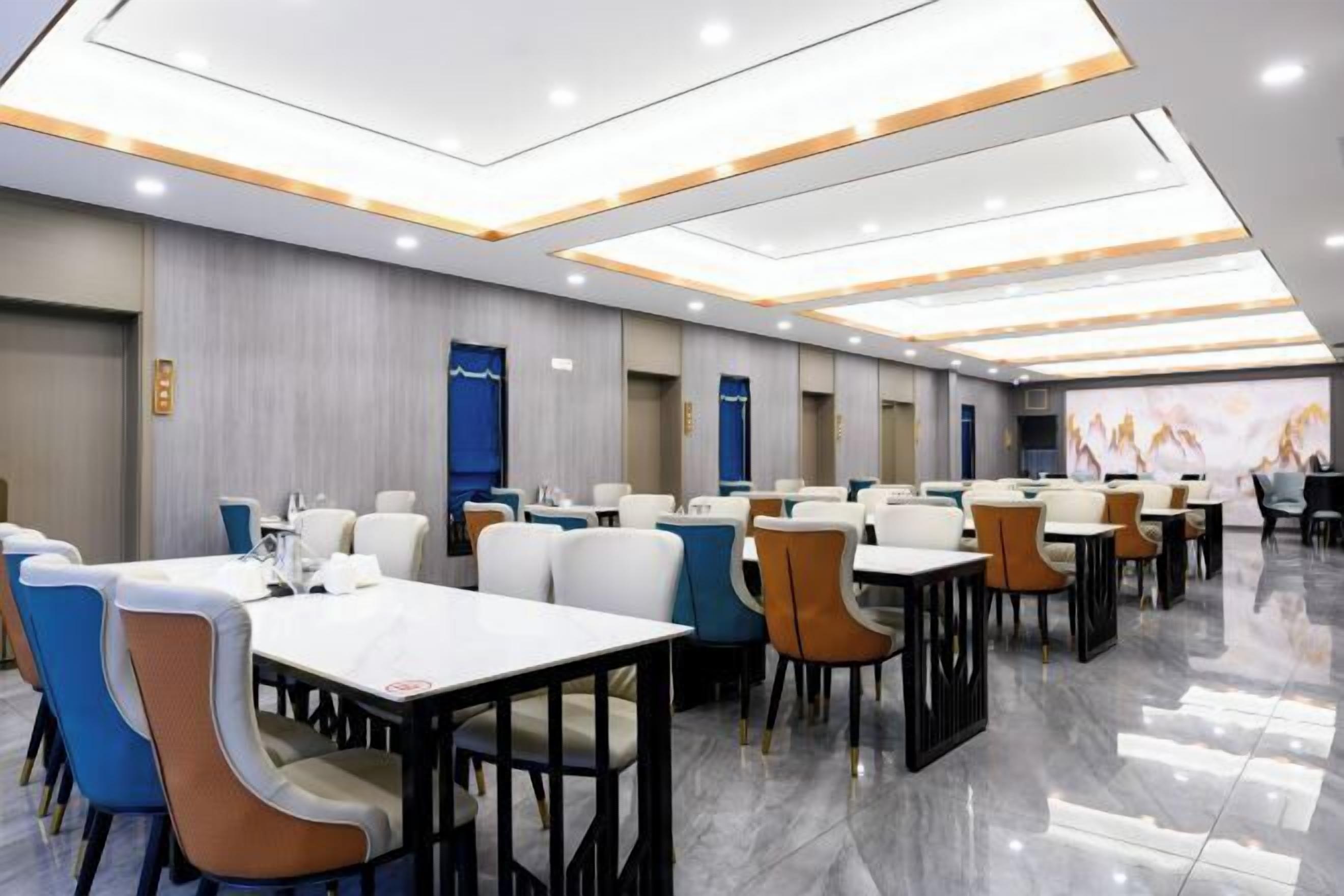 A modern conference room with tables and chairs, recessed ceiling lights, and a large screen for presentations.