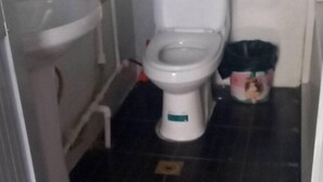 Ein Badezimmer mit Toilette, Mülleimer und Fußbodenabfluss.
