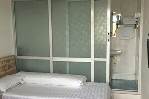 A room with a bed, a window with frosted glass, and a bathroom with a towel rack.