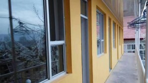 Ein Korridor mit großen Fenstern, einer gelben Wand und einem Metallgeländer.
