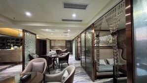 A hotel lobby with a seating area, a reception desk, and a decorative wall. - Olive Tree Hotel(Xuhai Times Jianyang Middle School Square) (Jianyang)