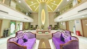 A lobby with purple sofas, a central reception desk, and a unique ceiling design. - Olive Tree Hotel(Xuhai Times Jianyang Middle School Square) (Jianyang)