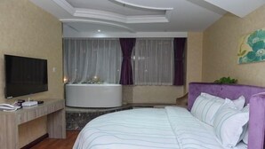 A hotel room with a bed, a TV, a desk, and a bathtub. - Olive Tree Hotel(Xuhai Times Jianyang Middle School Square) (Jianyang)