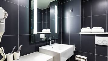 Ein modernes Badezimmer mit einem großen Spiegel, zwei Waschbecken, einem Föhn und einem Handtuchhalter.