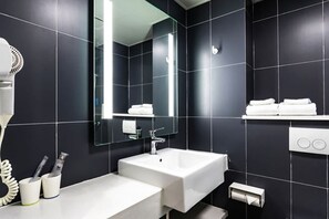 Un baño moderno con un espejo grande, dos lavamanos, un secador de pelo y un perchero para toallas.