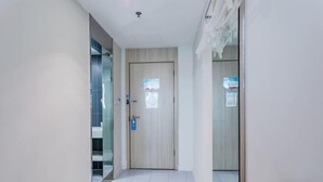 Un pasillo con una puerta, un banco y un separador de vidrio.