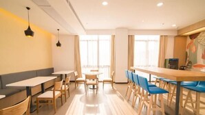 Una cafetería moderna con mesas de madera y sillas azules, ventanas amplias y un ambiente luminoso.