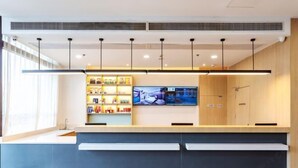 Una moderna zona de recepción con mostrador, estanterías con productos, televisor y un mueble de madera.