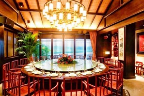 A round dining table with chairs, a chandelier, and a view through large windows. - Sante Langkou Club (Chongyang)