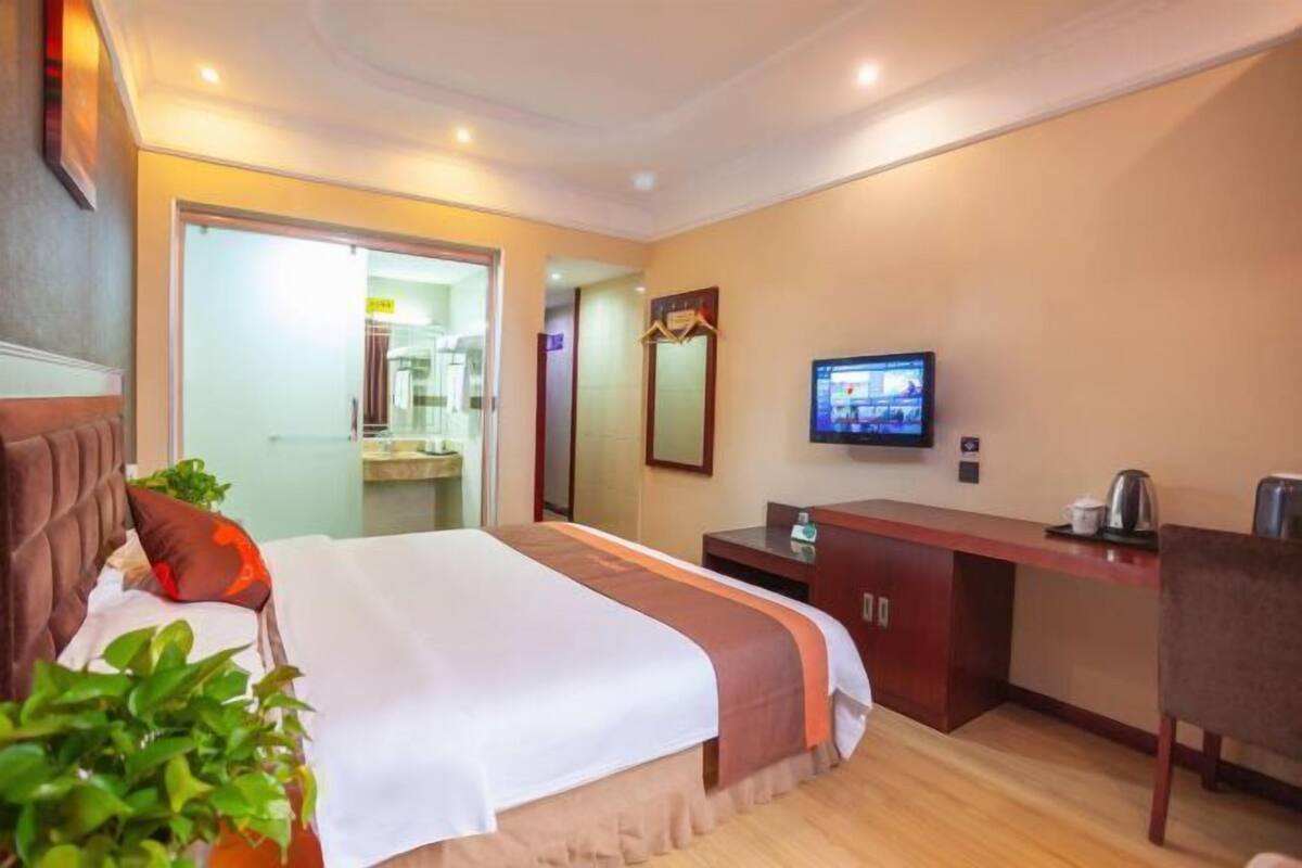 A hotel room with a bed, a desk, a television, and a mirror.