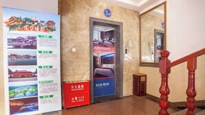 Een hotelentree in traditionele Chinese architectuur, met een JUM Hotels bord en informatieposters aan de muur.