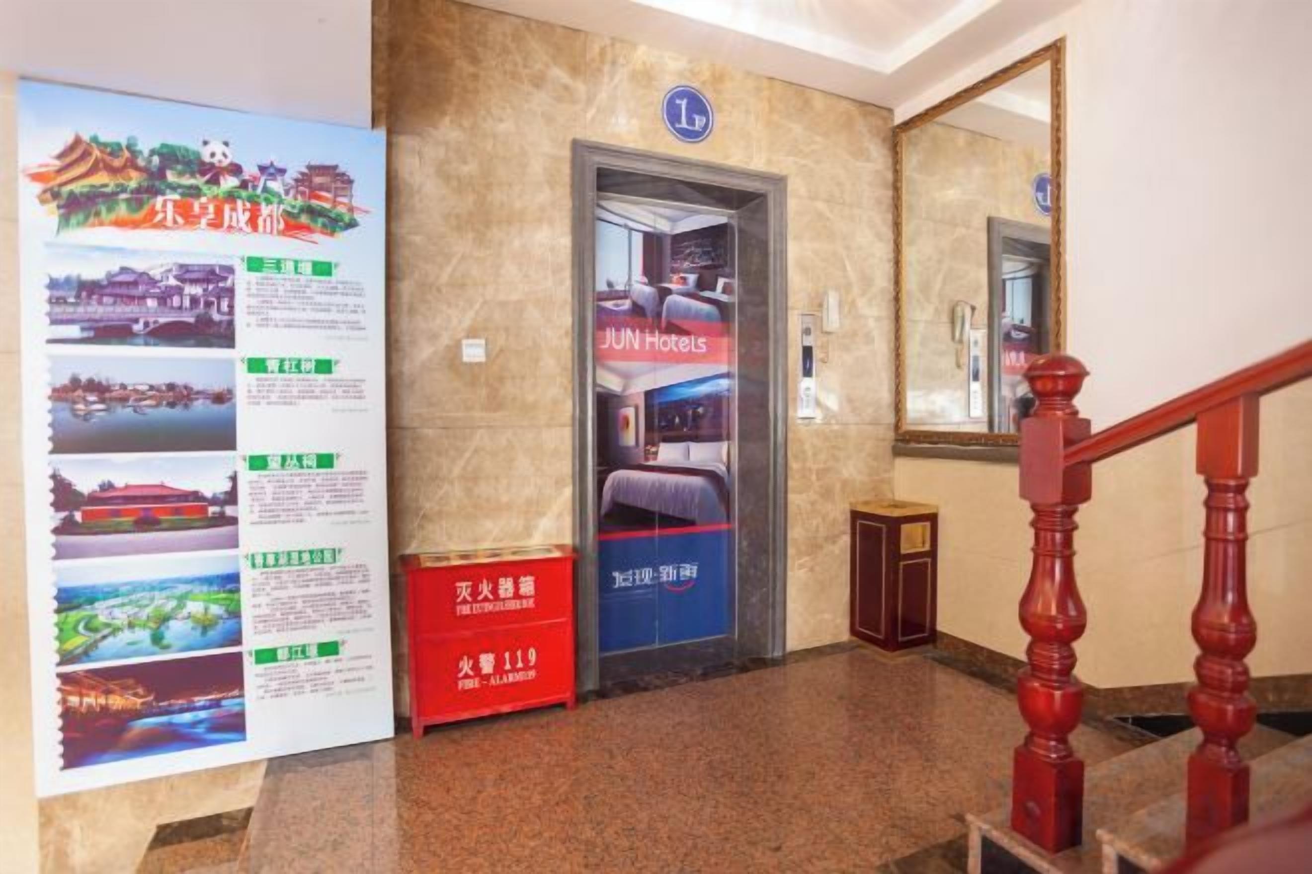 A hotel entrance with a reception desk, a poster with information, and a staircase.