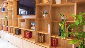 Een houten boekenkast met boeken, decoratieve objecten en een televisie.