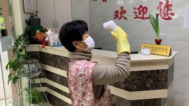 A reception desk with a sign indicating a place to display identification. - Jixi School Hotel (Jixi)