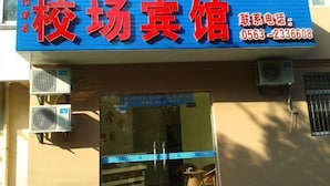 A building with a blue signboard displaying the name and contact number of a business. - Jixi School Hotel (Jixi)