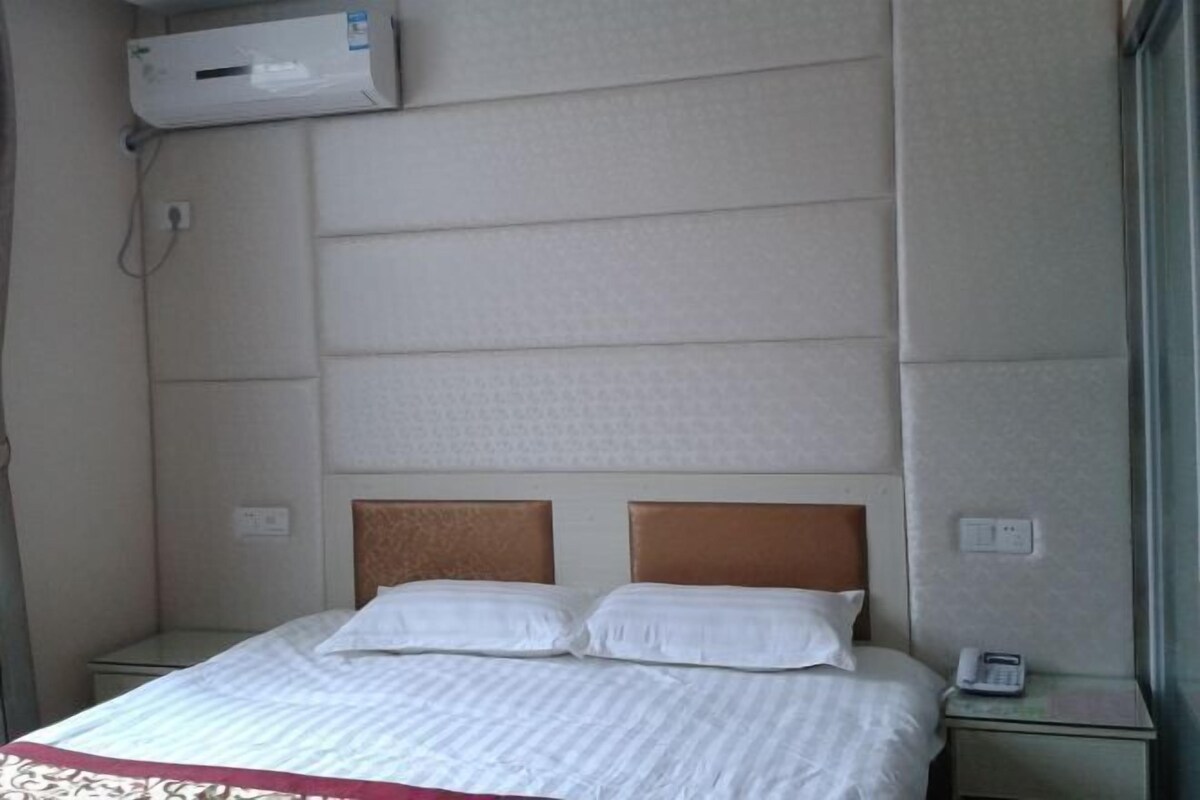 Et hotelværelse med en seng, et sengebordstelefon og en aircondition på væggen.
