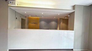 A reception desk with a modern design, featuring a neutral color palette and a logo on the back wall. - Homeinn · neo (Nanchang Xianghu Wetland Park Jiangling Subway Station) (Nanchang)