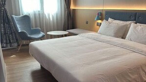 A hotel room with a large bed, a small round table, a blue chair, and a view of the outdoors through the window. - Homeinn · neo (Nanchang Xianghu Wetland Park Jiangling Subway Station) (Nanchang)