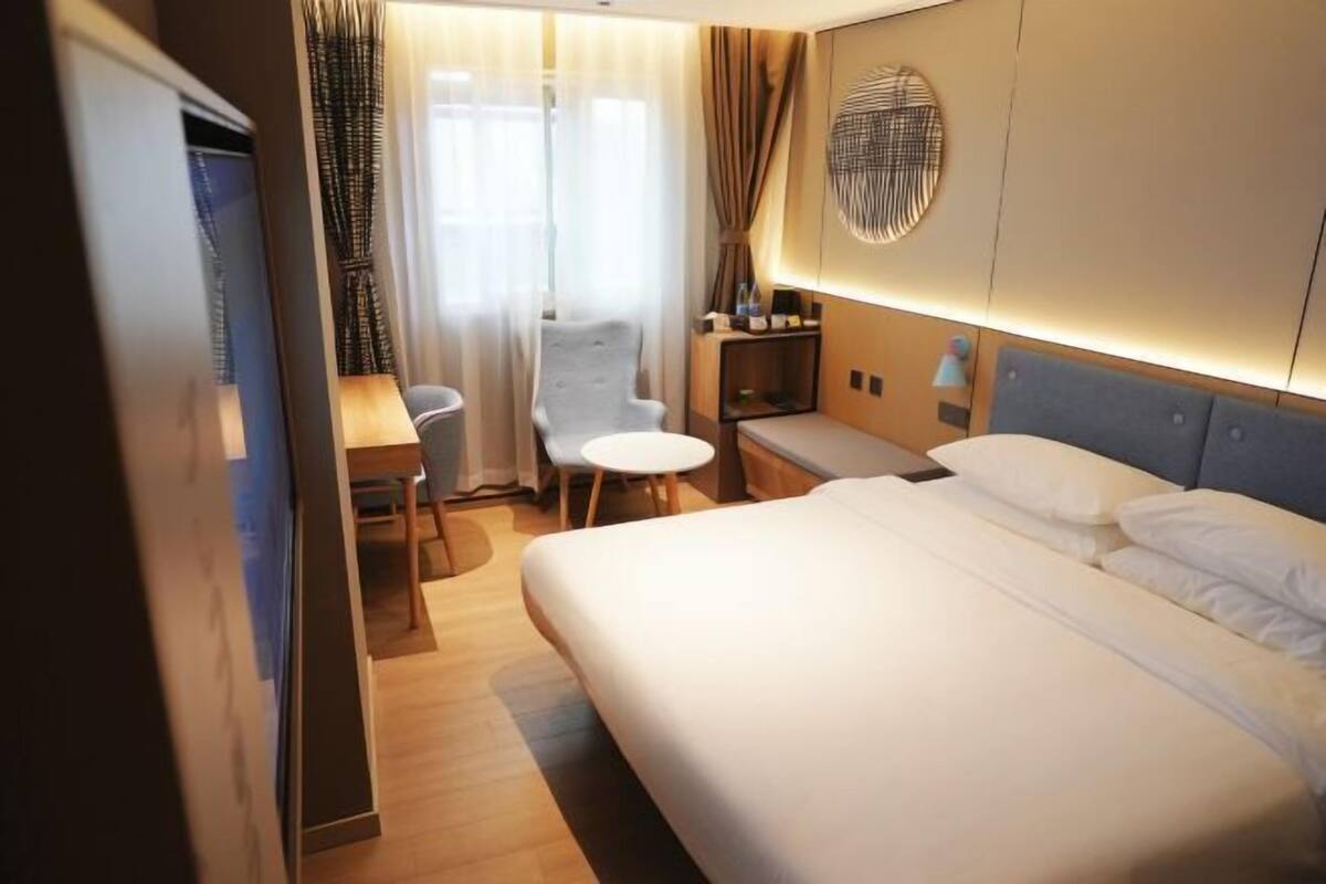 A hotel room with a bed, a desk, a chair, and a small table.