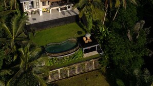 Vue aérienne d’un complexe hôtelier doté d’un bâtiment à toit de chaume, d’une piscine et d’une végétation tropicale luxuriante.