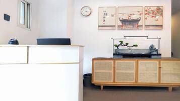 A reception area with a desk, a clock, and wall-mounted artwork.