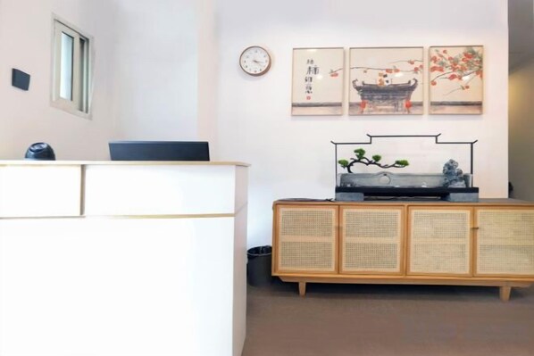 A reception area with a desk, a clock, and wall-mounted artwork. - Haoyun Hotel (Nanshida People's Hospital) (Nanjing)