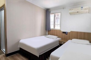 A hotel room with two beds, a window with curtains, an air conditioning unit, and a wooden headboard. - Haoyun Hotel (Nanshida People's Hospital) (Nanjing)