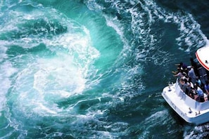 A boat with passengers, surrounded by turbulent ocean waves. - Awaji Central Room NC03 (Awaji)